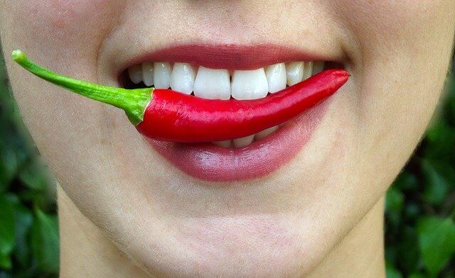 Imagen de una guindilla en la boca de una mujer
