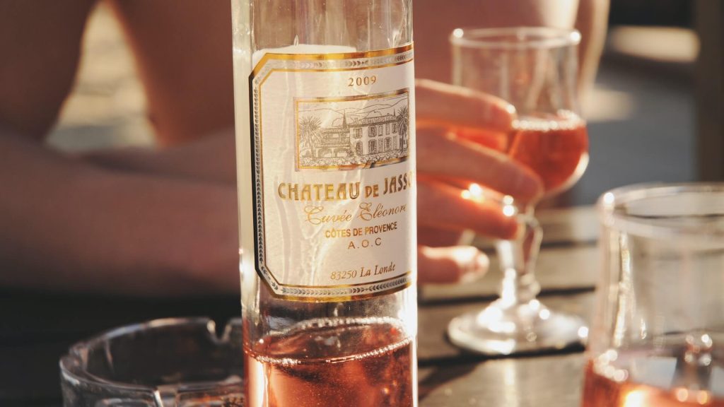 Una copa de vino rosado con una botella cerca